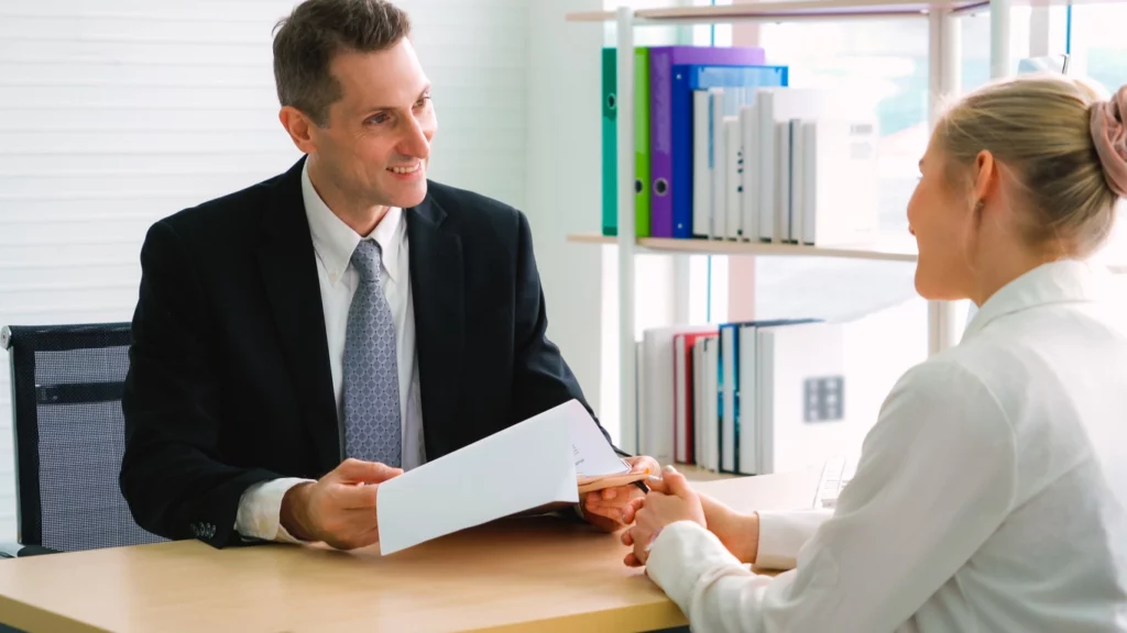 Un expert en crédit investissement locatif qui conseille une femme non-résidente sur les différentes options de prêt immobilier pour investissement locatif