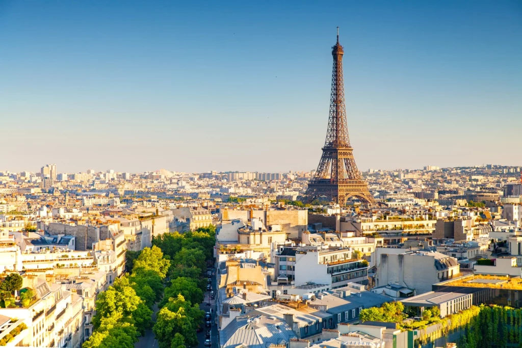 Un investisseur expatrié contemple la skyline de Paris depuis un rooftop, plan d'investissement en main, prêt à franchir le cap.