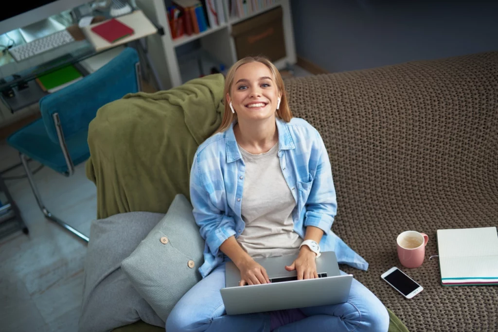 Une jeune fille posée dans son canapé, tout confortable dans son logement étudiant à vannes.