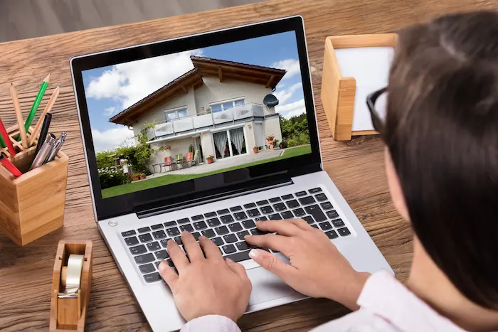 Photo d'une femme agente immobilière qui scrute une plateforme d'investissement immobilier à distance.